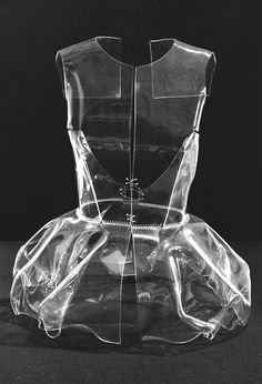 the back of a clear plastic dress form on a black surface with no background or text