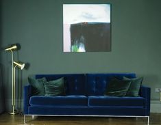 a blue couch sitting in front of a painting on the wall