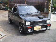 a small black car parked in front of a building