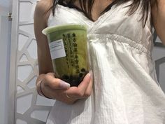 a woman holding up a cup with some sort of drink in it's hand