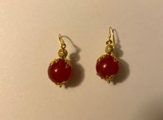 Beautiful, handmade, red-dyed jade earrings with a delicate golden leaf surrounding and nickel-free ear wire. Elegant Gold Carnelian Earrings, Elegant Carnelian Drop Earrings, Gold Carnelian Dangle Earrings, Gold Carnelian Jewelry With Matching Earrings, Gold Carnelian Earrings With Ear Wire, Carnelian Gold Earrings With Ear Wire, Red Carnelian Earrings Perfect As A Gift, Red Dangle Jewelry With French Hook, Handmade Red Ruby Earrings