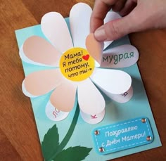 someone is making a flower out of paper and glues it on to the card