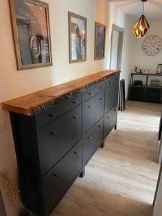 a kitchen with black cabinets and wooden counter tops in front of a clock on the wall