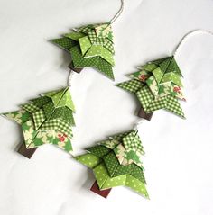 three green origami christmas decorations hanging on a white tablecloth with polka dots