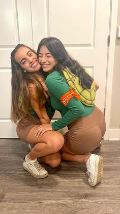 two young women hugging each other in front of a white door and wood flooring