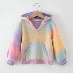 a colorful sweater hanging on a hanger with a white wall in the back ground