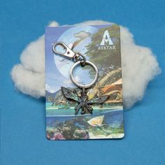 a keychain that is shaped like a dragon on a blue background with clouds in the foreground