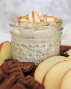 an apple dessert in a glass jar surrounded by cookies and crackers