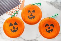 three orange paper plates with jack - o'lanterns on them sitting on a marble surface