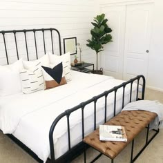 a bed with white sheets and black metal frame