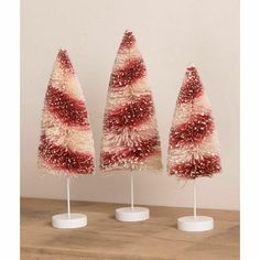 three red and white christmas trees sitting on top of a wooden table