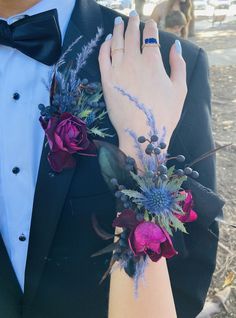 a man in a tuxedo with flowers on his wrist and an engagement ring