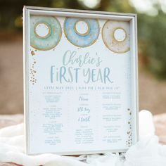 a baby's first year sign with doughnuts on it sitting on a blanket