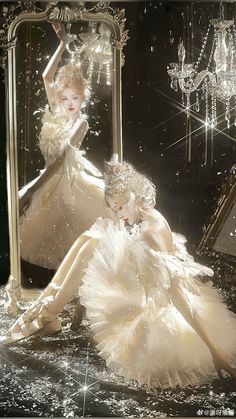 two women in white dresses are sitting on the floor next to a mirror and chandelier