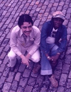 two young men sitting on the ground smiling