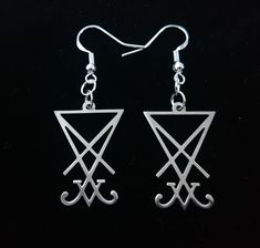 "Mini shiny stainless steel Sigil of Lucifer symbols for your ears! The Sigil of Lucifer contains an \"X\" which symbolizes power in this physical plane. The inverted triangle is a symbol for water and the \"V\" at the bottom symbolizes duality. The whole symbol looks like a chalice which represents creation. Earring hook is zinc alloy based and 925 Sterling silver plated. Charm measures 25 mm high(approx) Full length with hook 52 mm (approx) *Stainless Steel Closed Hinged Earring Hooks available upon request!*" Sigil Of Lucifer, Water Symbol, Earrings Gothic, Inverted Triangle, Earring Hook, Hook Earrings, Alchemy, Zinc Alloy, Favorite Jewelry