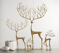 three deer and two giraffe sculptures in front of a white background with presents