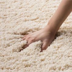 a person's hand on top of a white rug