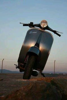 a silver scooter parked on top of a rock