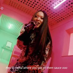 a woman singing into a microphone while standing in a room with pink walls and ceiling