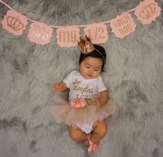 a baby girl wearing a pink and gold 1st birthday outfit