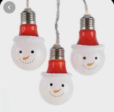 three light bulbs with snowmen on them hanging from wires in front of a white background