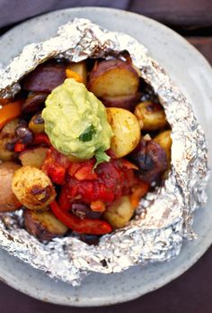 a white plate topped with potatoes covered in sauce and guacamole on top