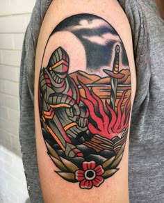 a man with a tattoo on his arm holding a knife and fork in front of a fire