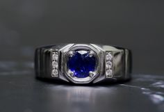 a close up of a ring with a blue stone in the center and diamonds around it