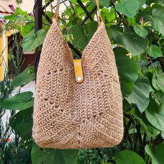 a handbag hanging from a tree with green leaves