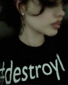 a woman wearing a black shirt with the word destroy written on it in white letters