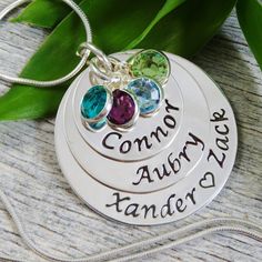 "~ This mom necklace features four names and four swarovski birthstones.  Depending on the length of the name I most likely can fit a second name on the middle disc for a total of five names.  If you add a name and need to add a birth stone there is a link below for that: https://www.etsy.com/listing/176471760/add-a-birthstone?ref=shop_home_active_1 ~ This pendant consists of three discs measuring at 3/4\", 1\" and 1 1/4\" (22 gauge). ~ All metal elements are Sterling Silver. ~ The necklace shown was stamped with the Lucida font.    WHAT I NEED TO COMPLETE YOUR ONE OF A KIND NECKLACE  ~ When ordering please include the following information in \"note to seller\", a convo or email:  * the names you want stamped and on which discs  * spacer for the largest disc: heart, &, dot or blank space Silver Birthstone Pendant Necklace With Name, Silver Name Necklace For May Birthstone, Silver Name Jewelry For Birthday Gift, Silver Jewelry With Names For Birthday Gift, Silver Birthstone Necklace With Names For Birthday, Silver Name Jewelry For Mom, Silver Jewelry With Names For Mom, Sterling Silver Pendant With Names, Mother Necklace