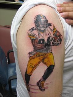 a man with a football player tattoo on his arm, holding the ball in one hand