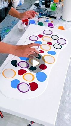 two people are painting circles on a table