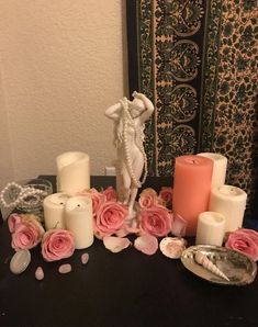 a table topped with candles and flowers next to a vase filled with pink rose petals