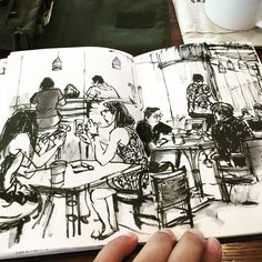 a person is holding an open book in their hand while they are sitting at a table