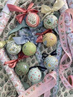 an assortment of decorated christmas balls and ribbons on a tablecloth with bows in the middle