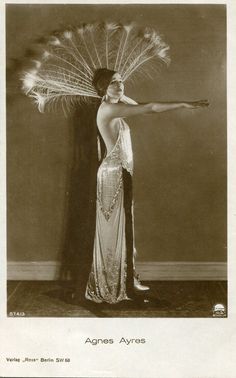 an old fashion photo of a woman holding a peacock