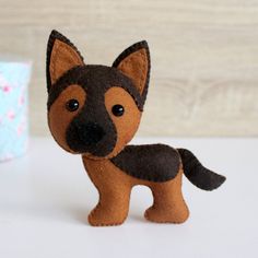 a small brown and black dog sitting next to a blue gift box on a white table