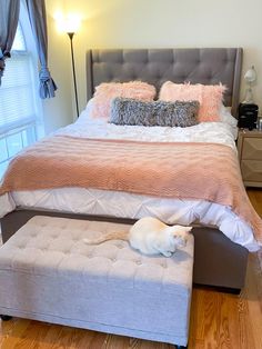 a dog laying on top of a bed next to a footstool in a bedroom