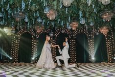 a man and woman dancing on a dance floor in front of hanging decorations with lights