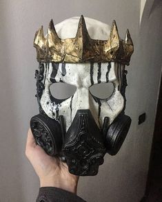 a person wearing a mask with gold crown on it's head and holding up their hand