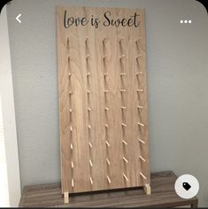 a wooden board with pegs attached to it that says love is sweet on the front