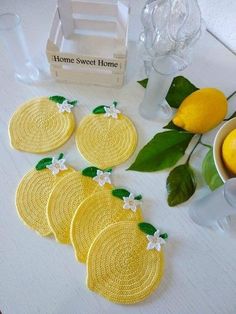 four lemon coasters sitting on top of a white table next to some lemons