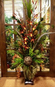 a vase filled with lots of different types of flowers and greenery next to a window