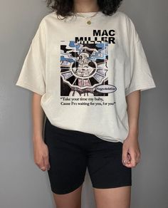 a woman standing in front of a wall wearing a t - shirt that says mac miller