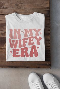 a t - shirt with the words in my wife era on it next to white shoes