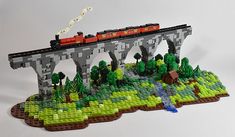 a lego model of a bridge with a train on it's tracks and trees