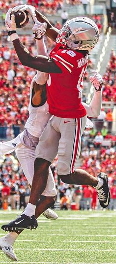 two football players collide in the air as they play against each other on a field