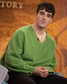 a man in a green sweater is sitting down